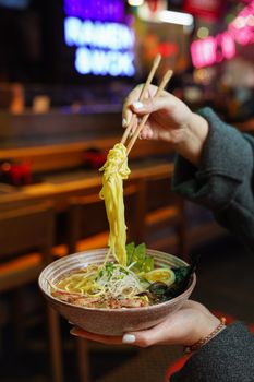 Tantalizing close-up of ramen noodles being lifted by chopsticks, emphasizing the vibrant ingredients and textures.