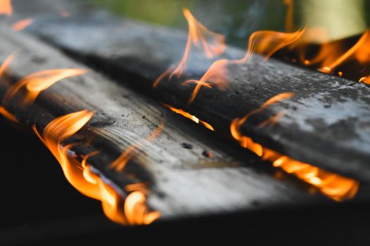 Vivid flames engulf wooden planks in an outdoor fire setting, showcasing warmth and energy.
